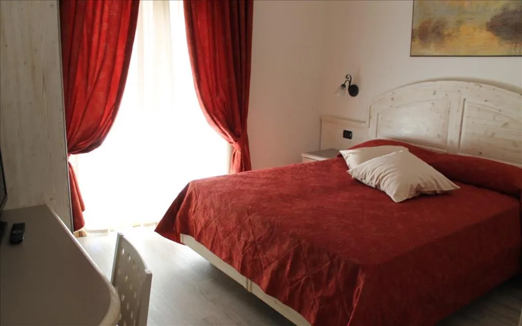 Camera con letto matrimoniale, copriletto rosso e finestra con tende rosse