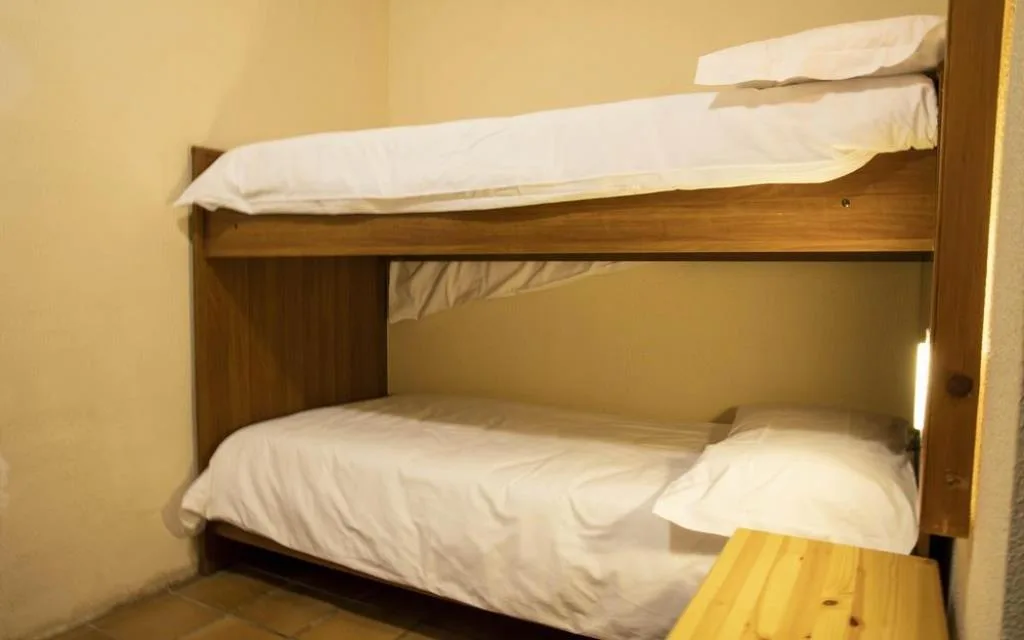 Letto a castello in legno con biancheria bianca e illuminazione soffusa