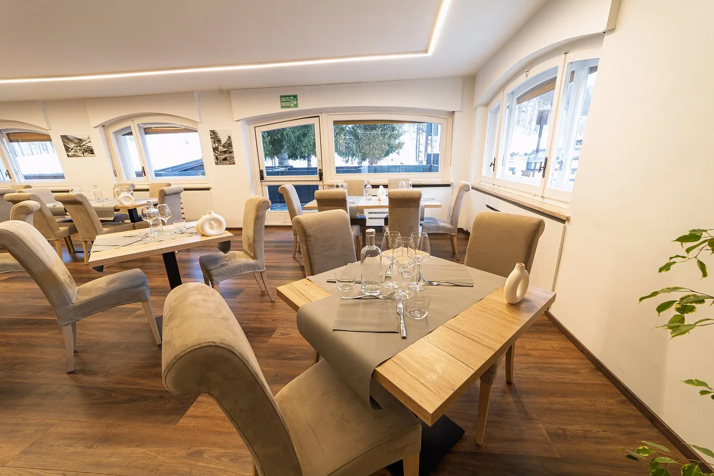 Interno ristorante con tavoli, sedie beige e vista sulla neve