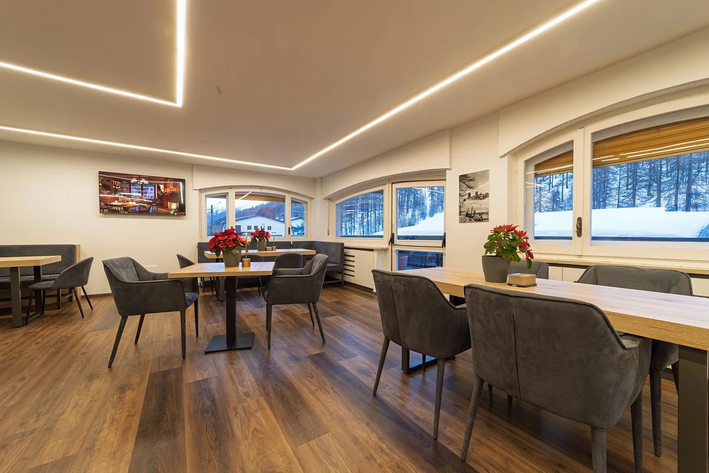 Sala comune moderna con tavoli, sedie grigie e vista sulla neve