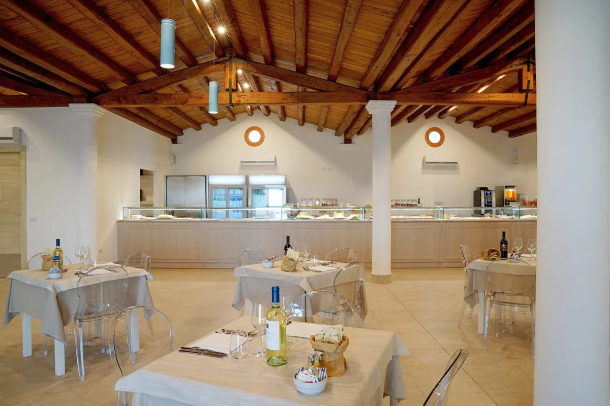 Sala ristorante con tavoli apparecchiati e soffitto in legno