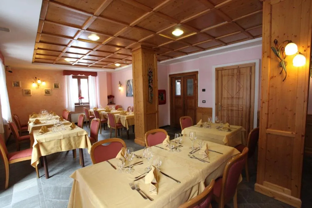 Sala da pranzo con tavoli apparecchiati, pareti rosa e arredi in legno