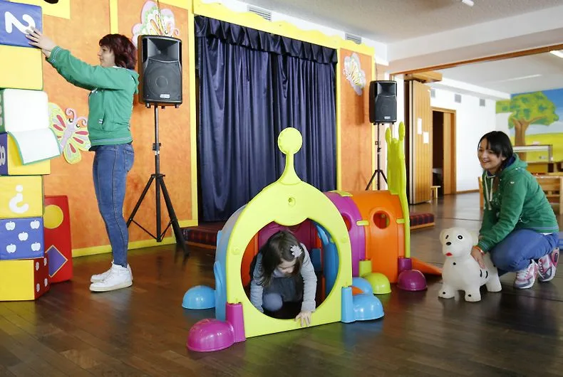 Sala giochi per bambini con animatrici, giochi colorati e angolo morbido