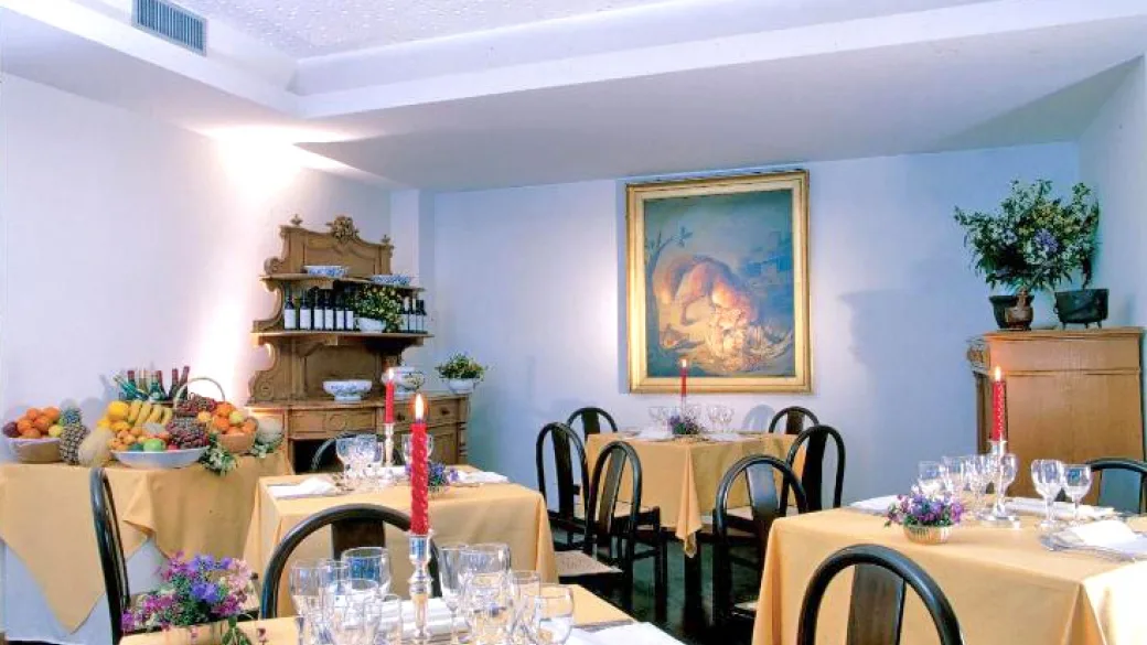 Sala ristorante elegante con tavoli apparecchiati, candele rosse e dipinto alla parete