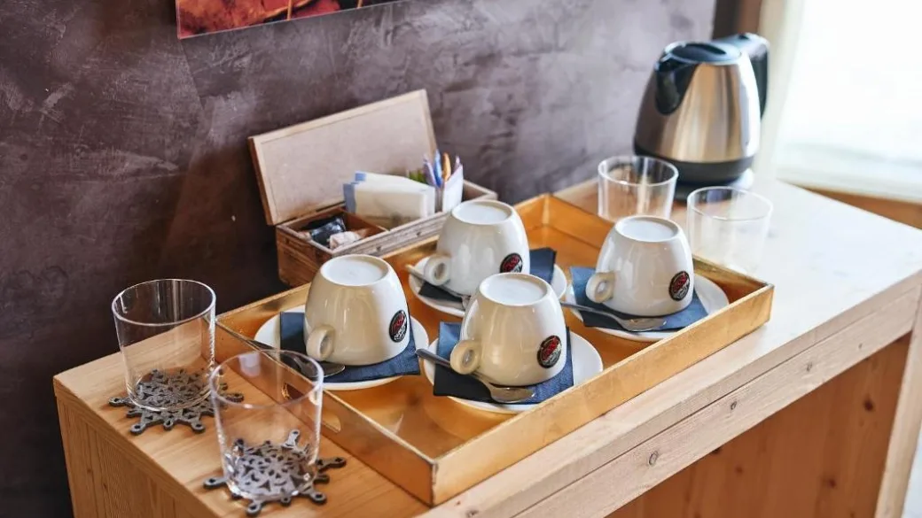 Vassoio con tazze da caffè, bicchieri e bollitore su mobile in legno