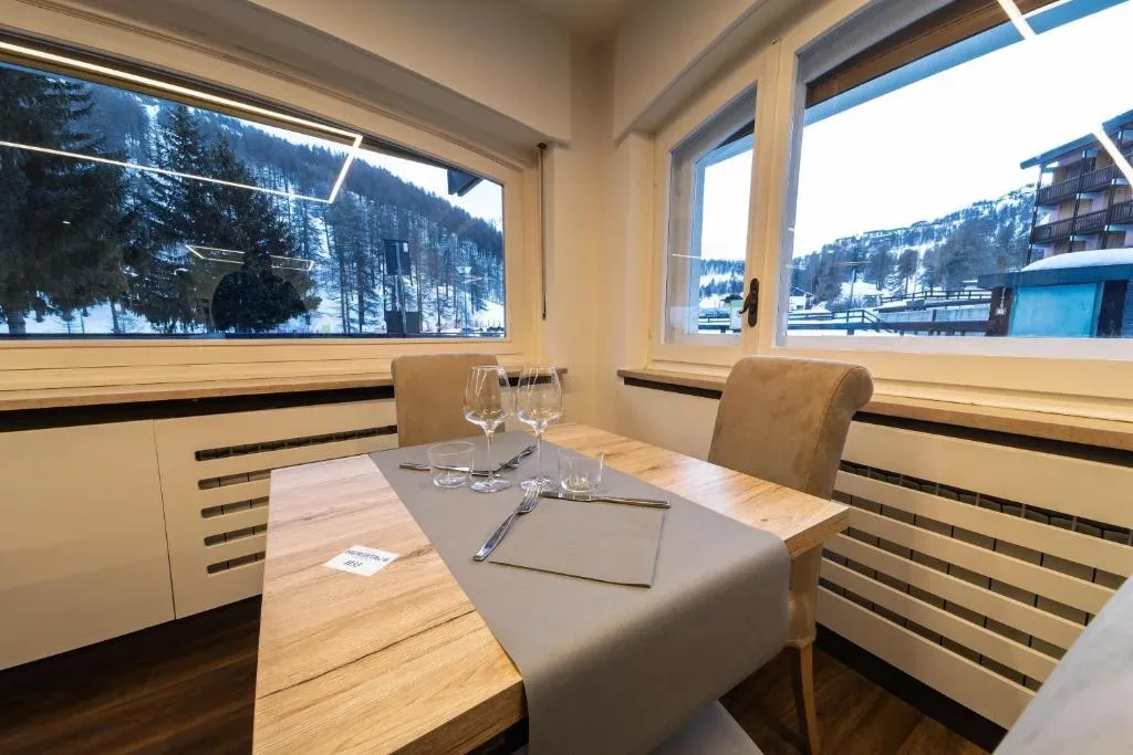 Tavolo apparecchiato accanto alle finestre con vista sulle piste innevate