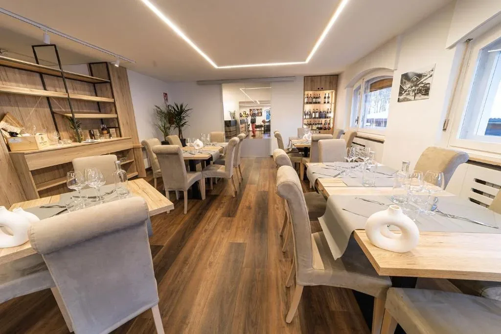 Sala da pranzo moderna con pavimento in legno e tavoli apparecchiati