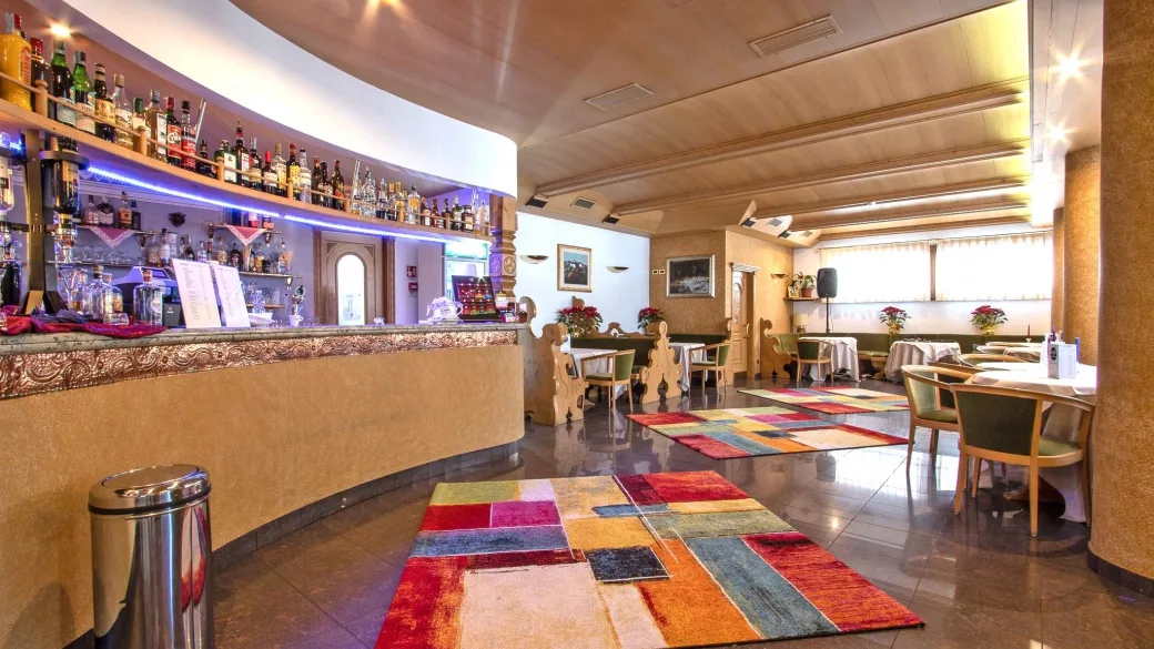 Area bar dell'hotel con bancone curvo e tappeti colorati