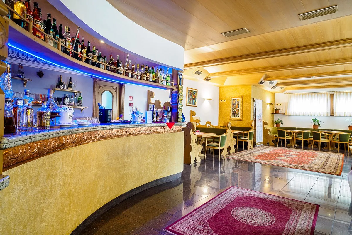 Bar dell'hotel con bancone dorato, bottiglie e tappeti orientali