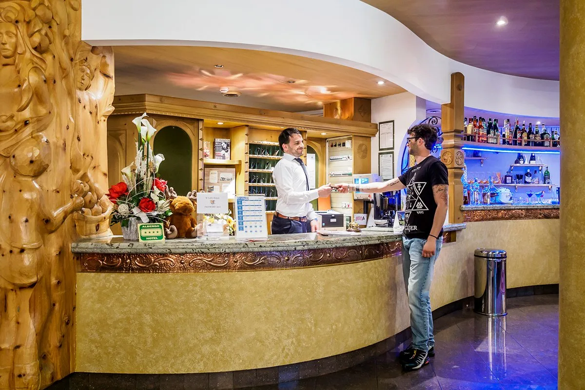 Reception dell'hotel con addetto che consegna le chiavi a un ospite