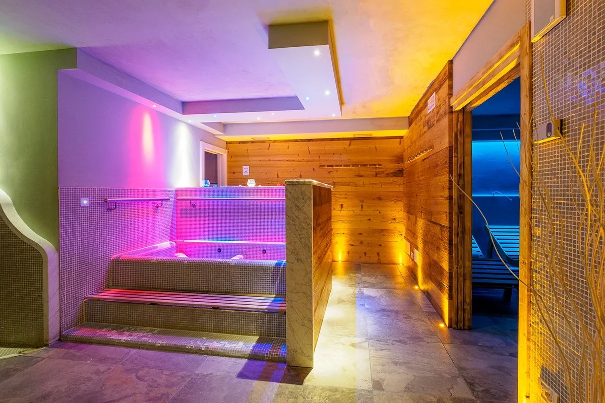 Centro benessere con vasca idromassaggio e pareti in legno illuminate