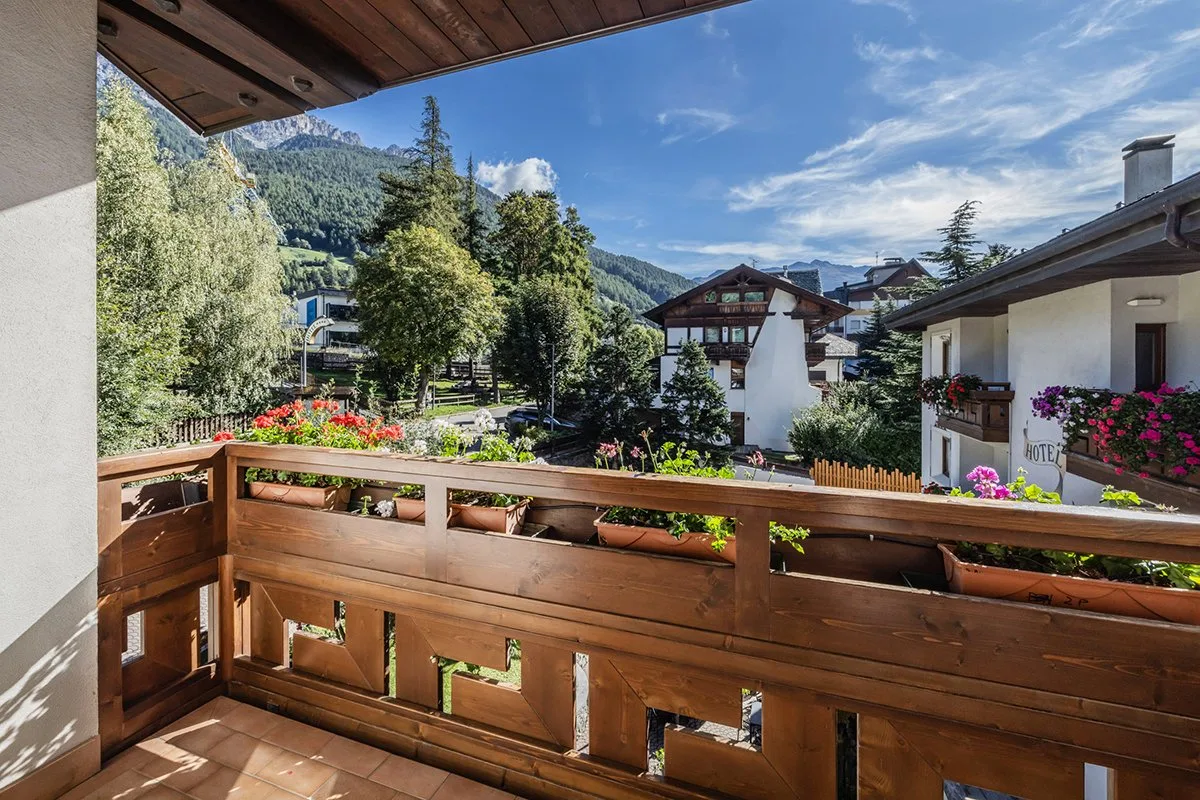 Vista dal balcone in legno con fiori sui tetti del paese e montagne verdi
