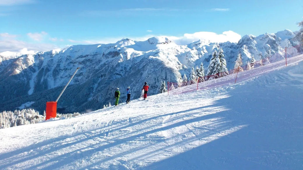 Sciatori su una pista innevata con panorama sulle cime montuose delle Dolomiti