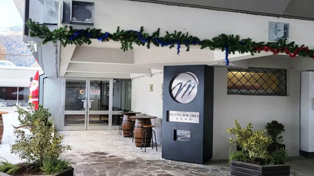 Ingresso dell'Hotel Solaria con insegna, decorazioni natalizie e tavolini a botte