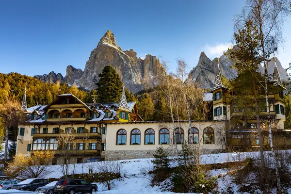 Hotel storico in stile tirolese immerso nella neve con le cime delle Dolomiti sullo sfondo