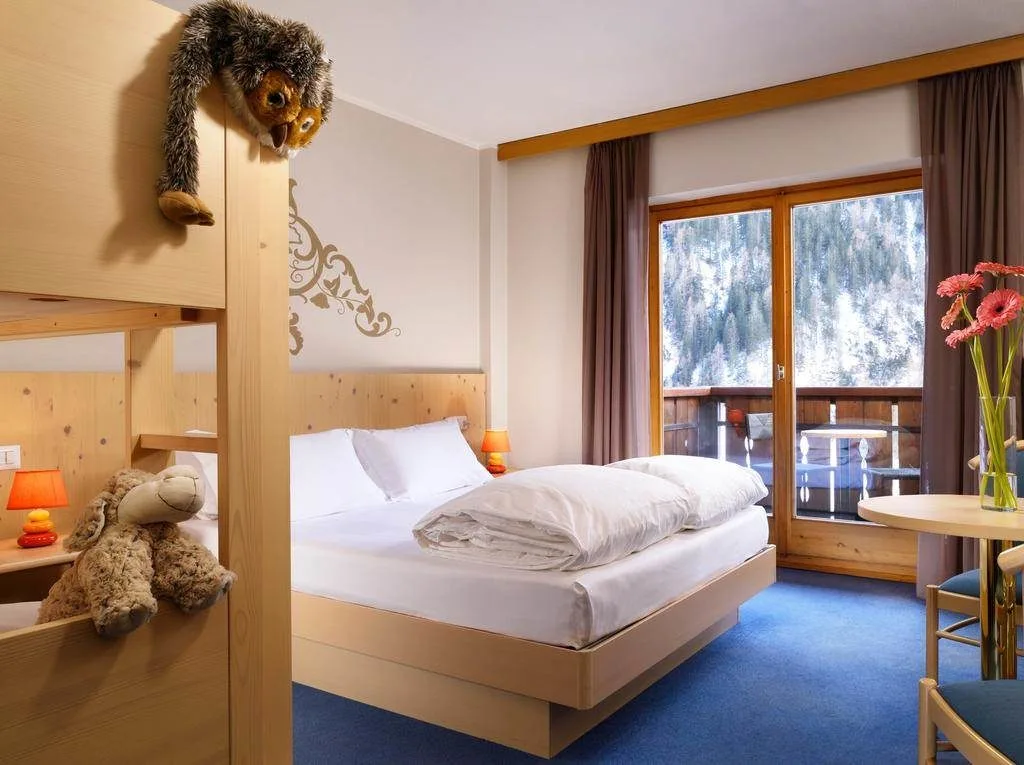 Camera familiare con letto matrimoniale, letto a castello e balcone affacciato sul bosco