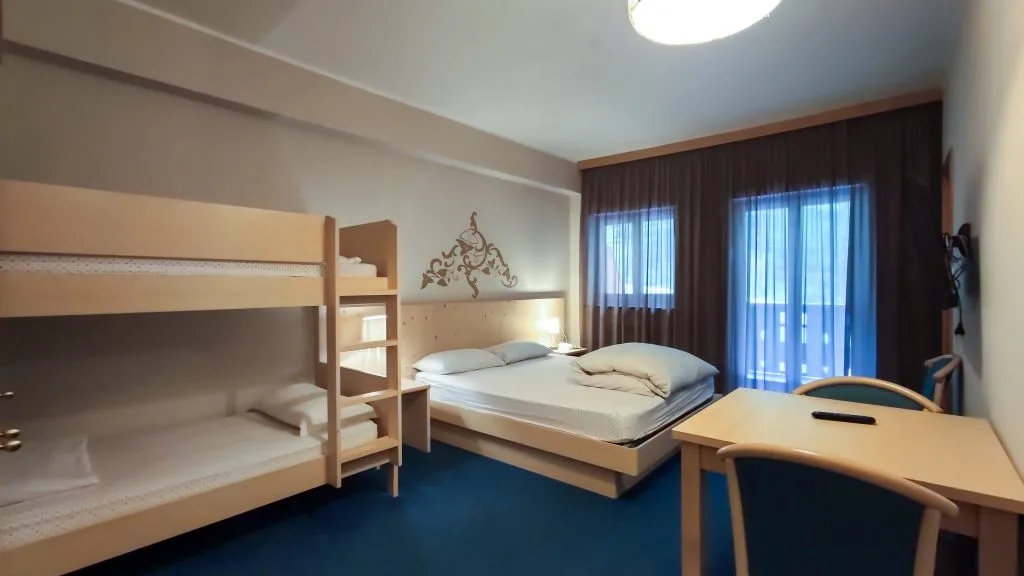 Camera con letto matrimoniale e letto a castello, scrivania e ampie finestre
