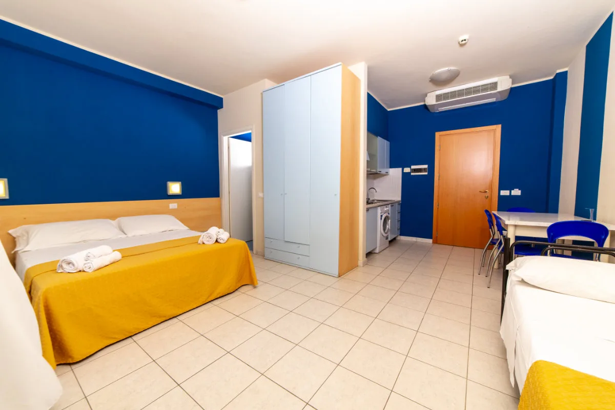 Appartamento con pareti blu, letto matrimoniale, angolo cottura e letto singolo