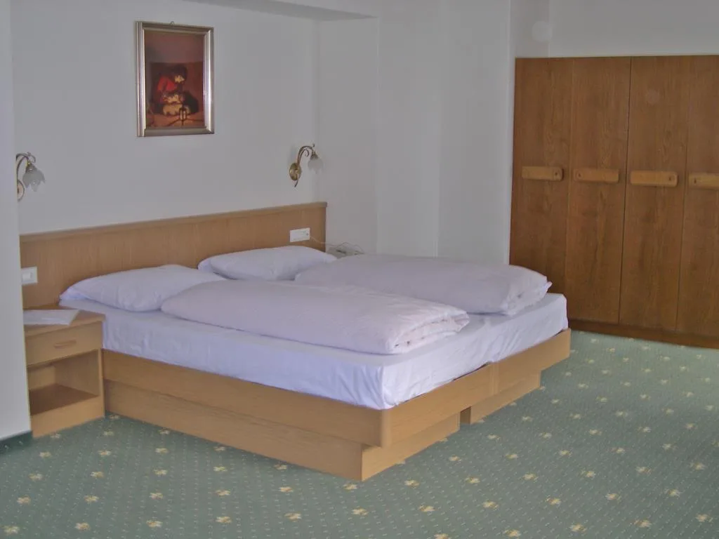 Camera matrimoniale con letto doppio, armadio in legno e moquette verde a fiori