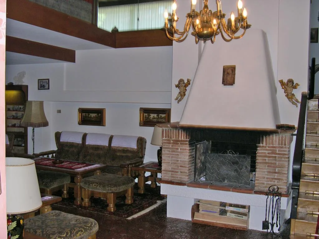 Salotto con camino in mattoni, divani imbottiti e lampadario dorato