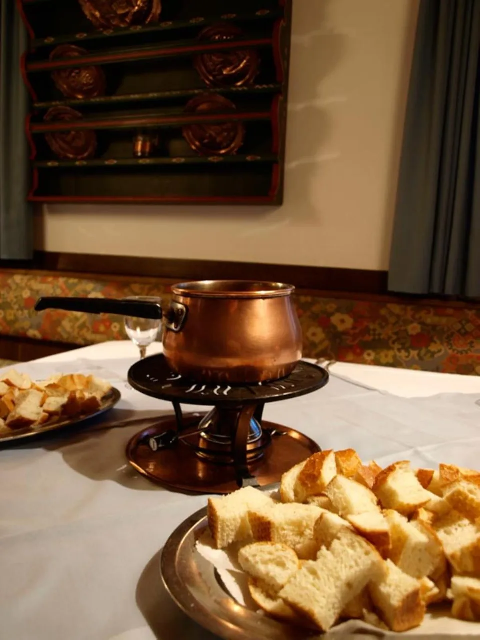 Fonduta servita con pentola in rame su fornello e pane a cubetti
