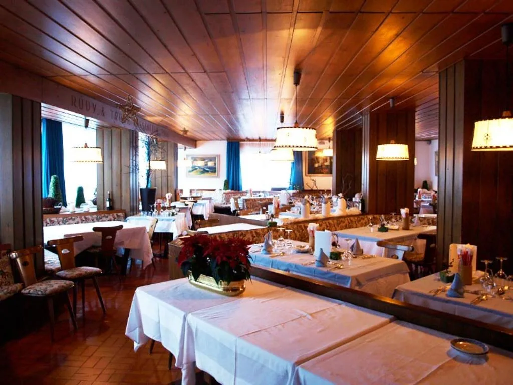 Sala da pranzo con soffitto in legno, tavoli apparecchiati e lampade sospese
