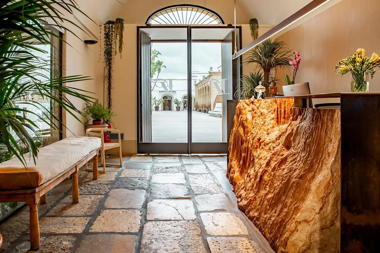 Hall con reception in pietra naturale, pavimento antico e piante verdi