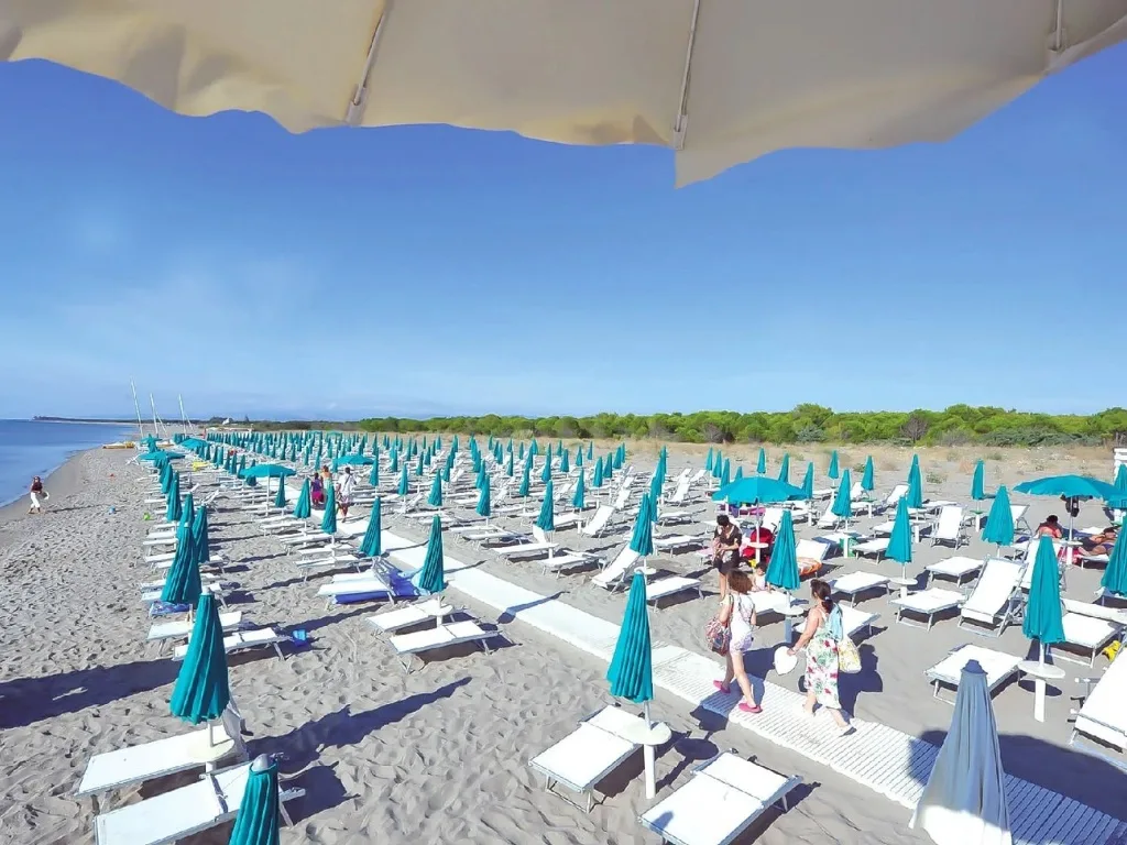 Spiaggia attrezzata con lettini e ombrelloni turchesi vista dal mare