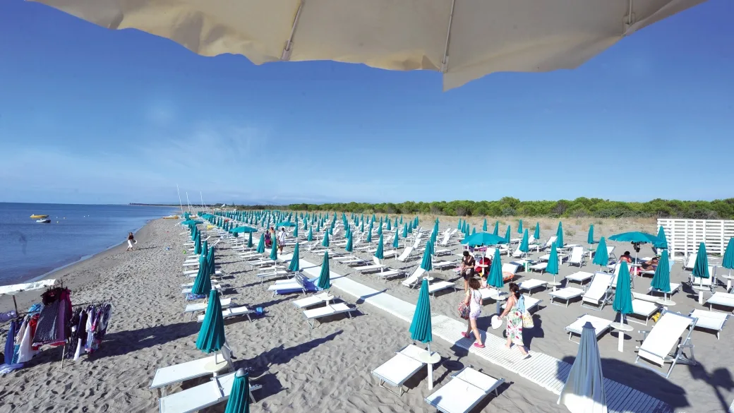 Spiaggia attrezzata con lettini e ombrelloni turchesi sul mare