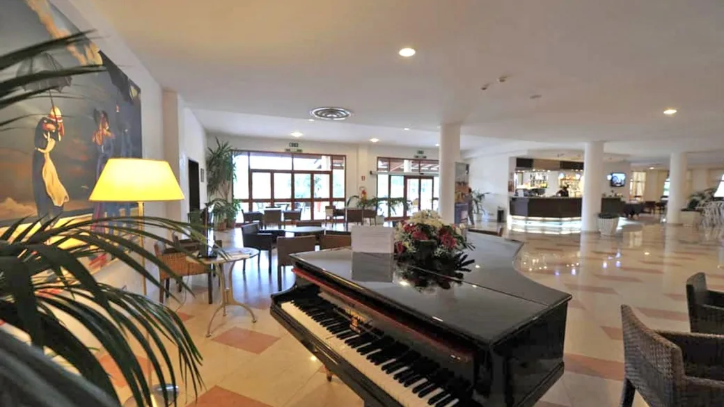 Hall dell'hotel con pianoforte a coda, divani e reception sullo sfondo