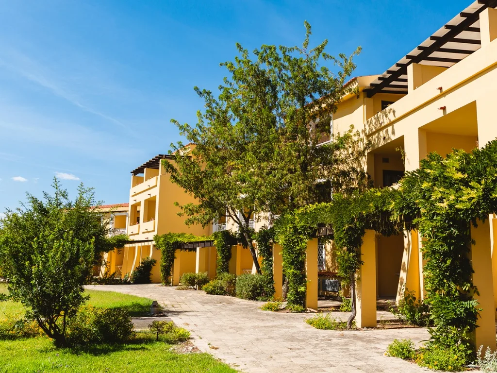 Camminamento tra gli edifici gialli del resort con giardini e pergolati di verde