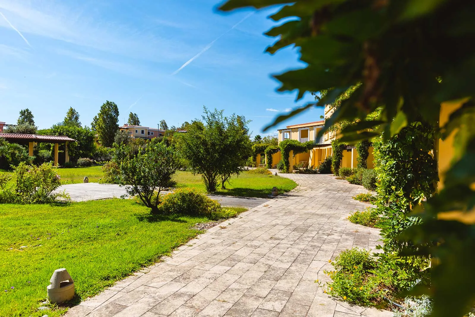 Vialetto pedonale del resort tra giardini verdi e edifici gialli