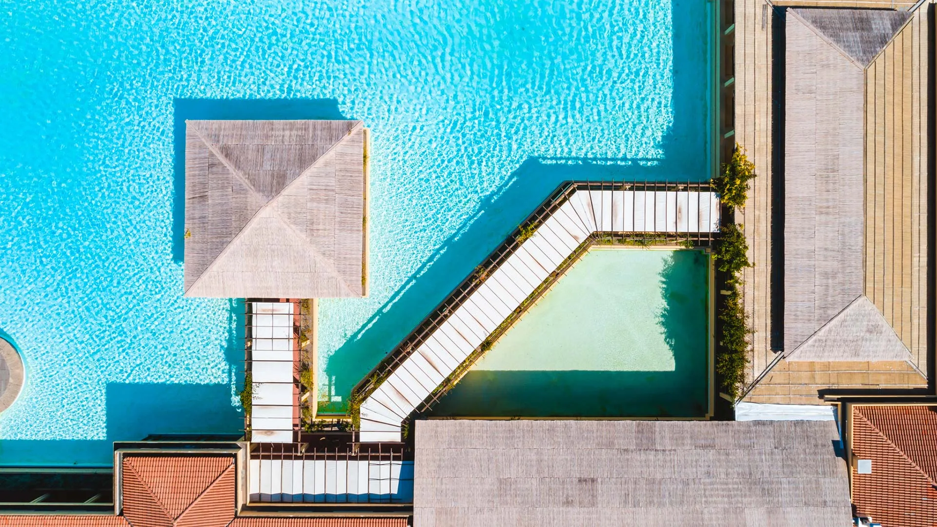 Vista aerea ravvicinata della piscina con gazebo in legno e passerella tra gli edifici