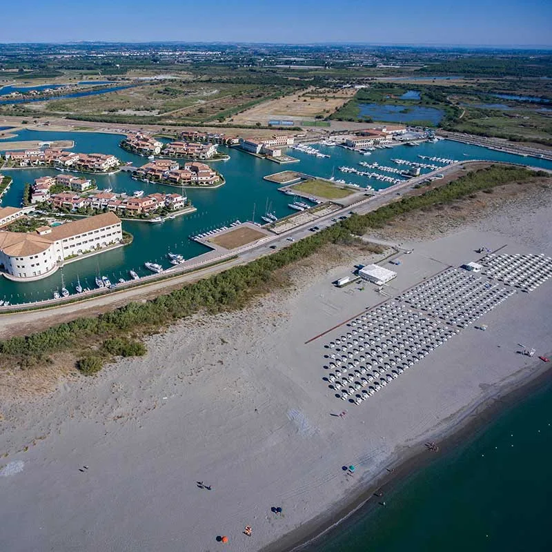 Veduta aerea del villaggio su isole con canali, porto turistico e spiaggia adiacente