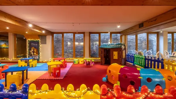 Area giochi per bambini colorata con casetta, tavolini e percorsi morbidi