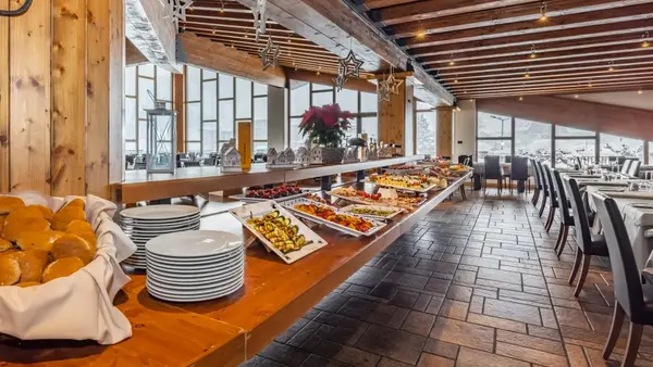 Buffet del ristorante con pane, piatti e varietà di pietanze su tavolo in legno
