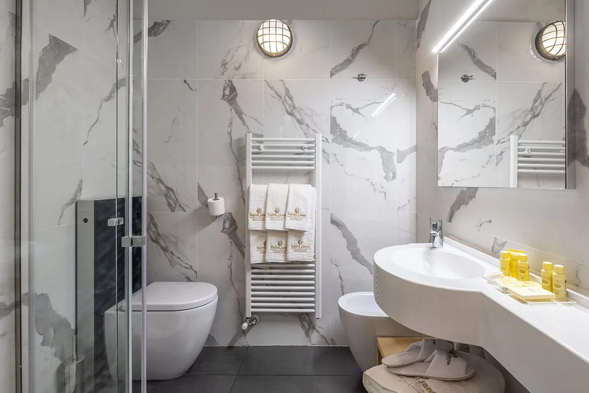 Bagno moderno con pareti in marmo, doccia, sanitari e asciugamani