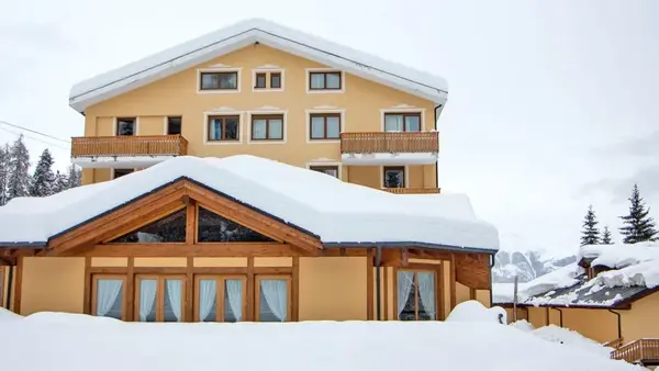 Edificio dell'hotel con veranda in legno e grandi finestre coperto di neve fresca