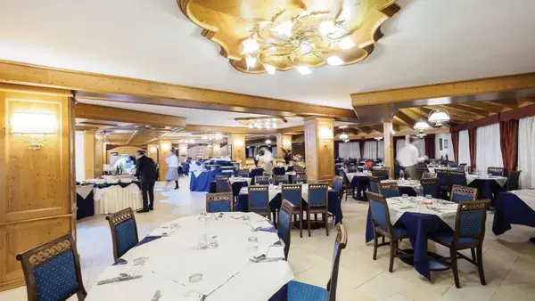 Sala ristorante elegante con tavoli apparecchiati, tovaglie blu e boiserie in legno