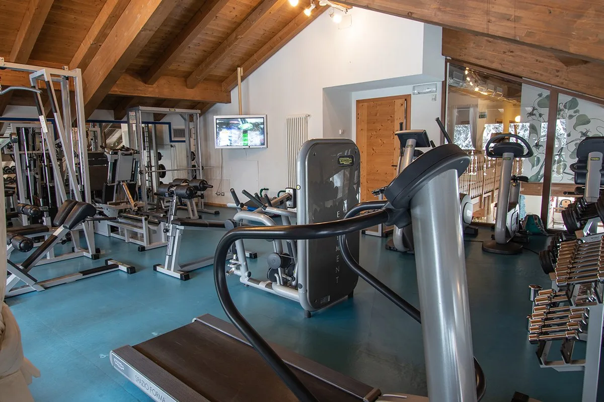 Sala fitness con attrezzi cardio, macchine Technogym e televisore a parete
