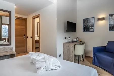Dettaglio della camera con letto, accappatoi, TV e zona ingresso