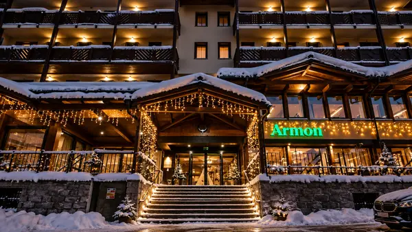 Ingresso dell'Hotel Armon illuminato con luci natalizie e neve di sera
