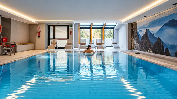 Piscina coperta con lettini e grande finestra panoramica sulle montagne