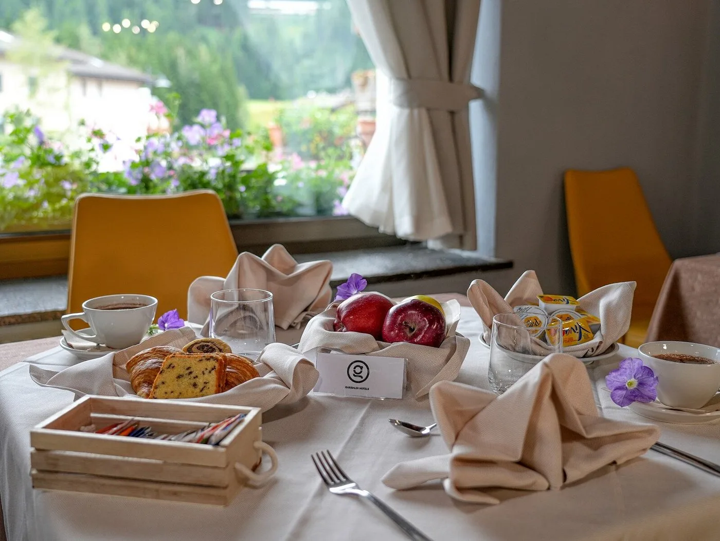 Tavolo apparecchiato per la colazione con dolci, frutta e vista sul giardino fiorito