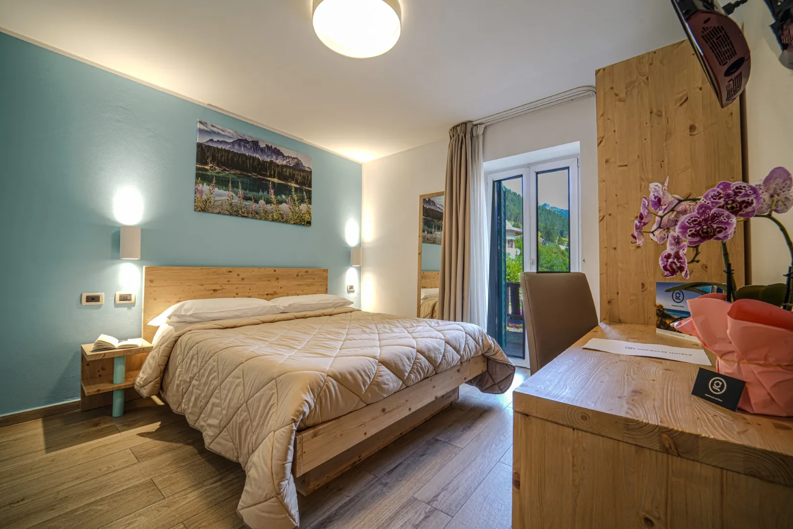 Camera moderna con parete azzurra, letto in legno e accesso al balcone