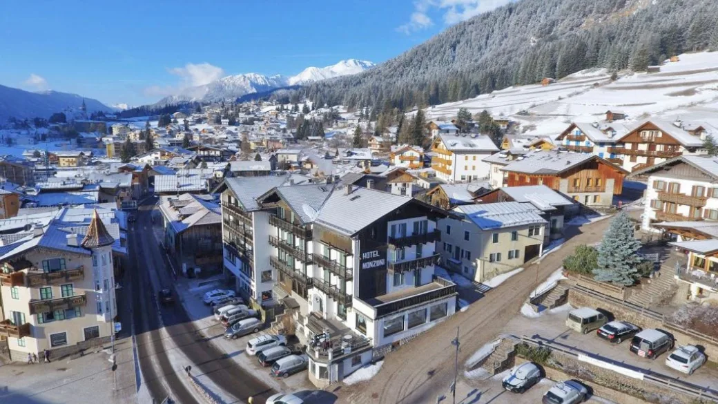 Vista aerea dell'Hotel Monzoni nel centro del paese innevato tra le montagne