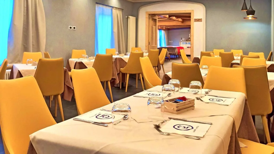 Sala ristorante con tavoli apparecchiati e sedie gialle moderne
