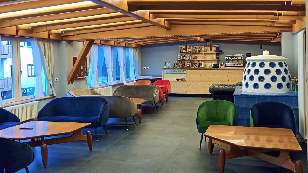 Lounge bar con divani colorati, travi in legno e stufa in maiolica