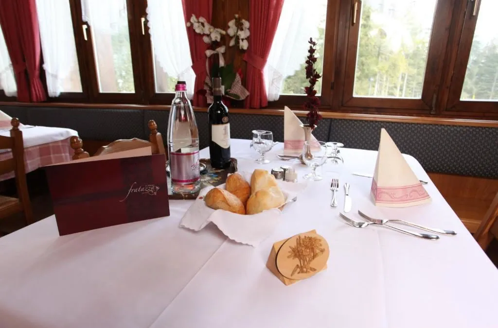 Tavolo apparecchiato del ristorante con cestino di pane, vino e acqua davanti alle finestre