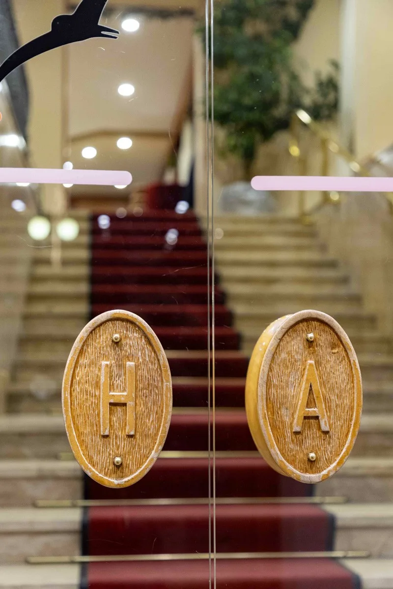 Dettaglio dell'ingresso con lettere HA e scala con tappeto rosso